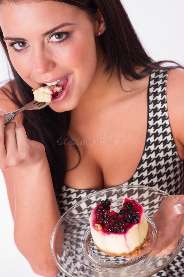 Mujer morena atractiva de la composición vertical que come los dulces foto de archivo libre de regalías Mujer morena atractiva de la composición vertical que come los dulces foto de archivo libre de regalías