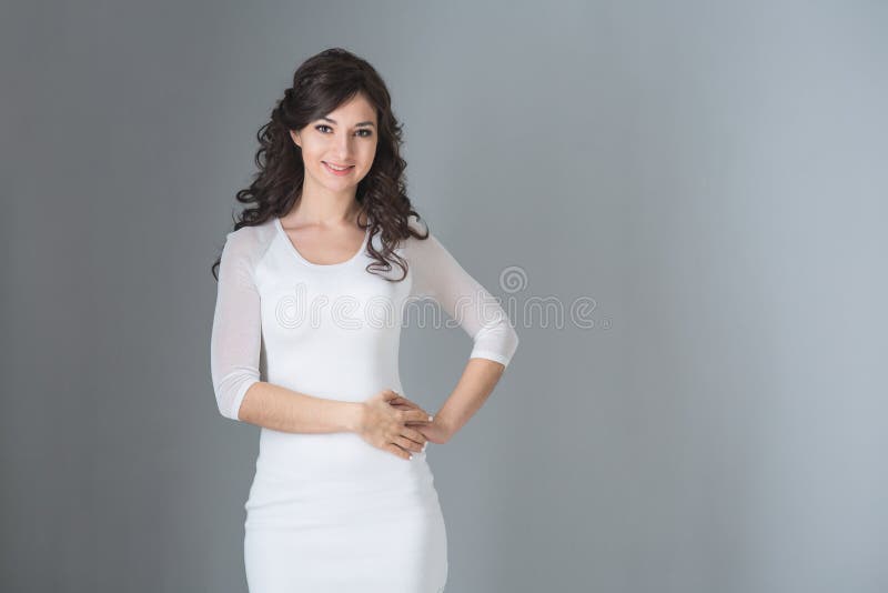 Mujer morena en el vestido blanco en fondo gris fotos de archivo libres de regalías Mujer morena en el vestido blanco en fondo gris fotos de archivo libres de regalías