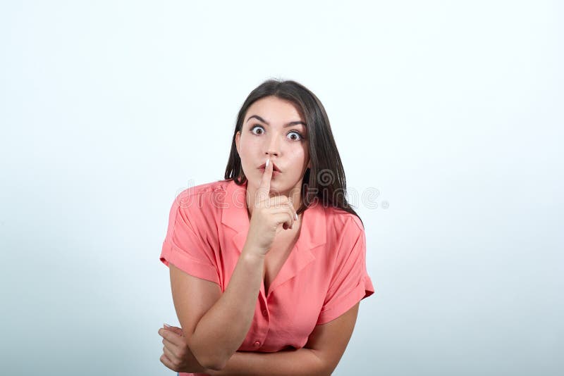 Mujer mostrando un gesto de silencio metiendo el dedo en la boca en blanco imagen de archivo libre de regalías Mujer mostrando un gesto de silencio metiendo el dedo en la boca en blanco imagen de archivo libre de regalías