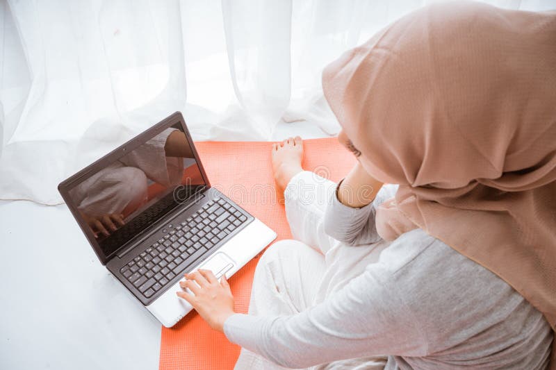 Mujer musulmana con hijab mirando a casa trabajo en tutorial desde laptop imagenes de archivo