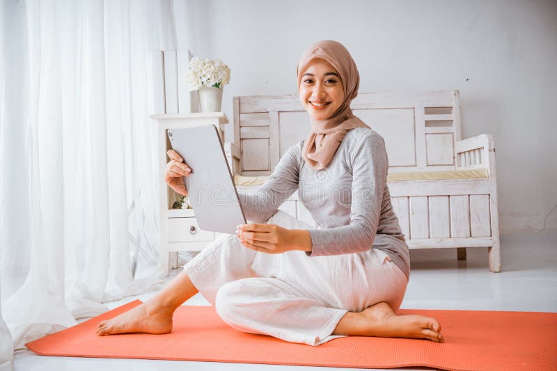 Mujer musulmana hijab mirando a su casa hace el tutorial desde tablet imagen de archivo libre de regalías