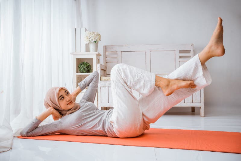 Mujer musulmana hijab se calienta antes de hacer ejercicio haciendo posadas de yoga foto de archivo libre de regalías