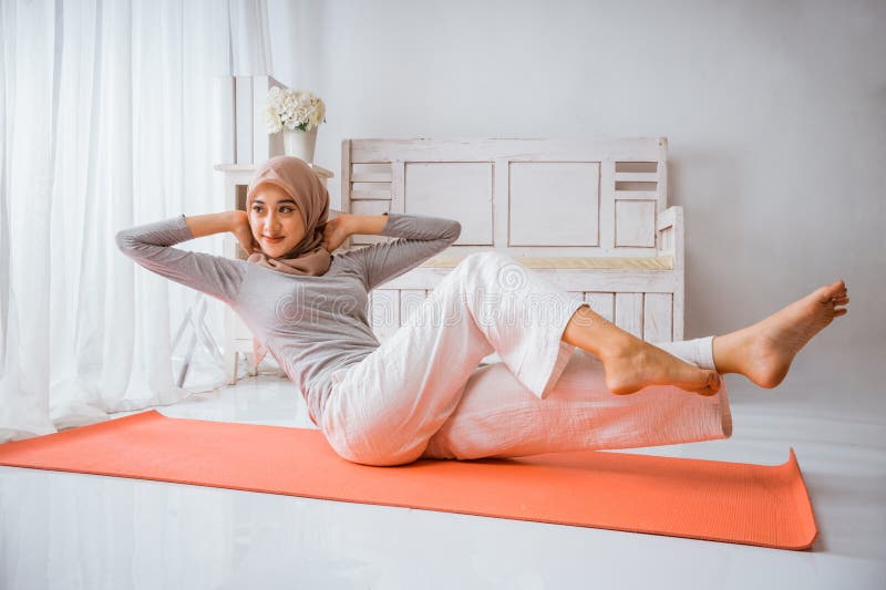 Mujer musulmana hijab se calienta antes de hacer ejercicio haciendo posadas de yoga imagen de archivo