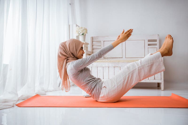Mujer musulmana hijab se calienta antes de hacer ejercicio haciendo posadas de yoga fotos de archivo libres de regalías