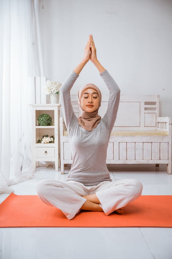 Mujer musulmana sana con hijab haciendo pilates de yoga meditando sobre colchón imagen de archivo libre de regalías