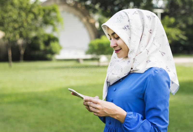 Mujer musulmán del hijab que usa smartphone en el parque fotografía de archivo libre de regalías
