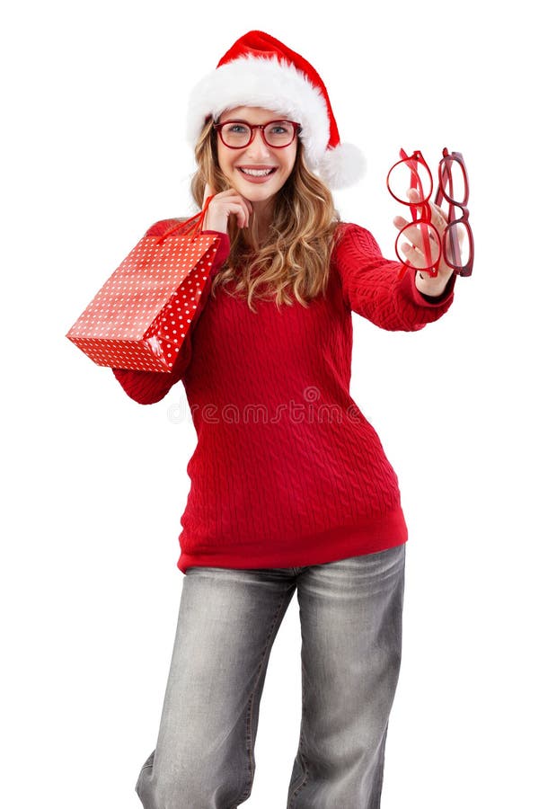Mujer navideña sonriente usa lentes rojos y sombrero de santa. portando bolsas de compras y mostrando modelos de espectáculos aisl fotos de archivo libres de regalías