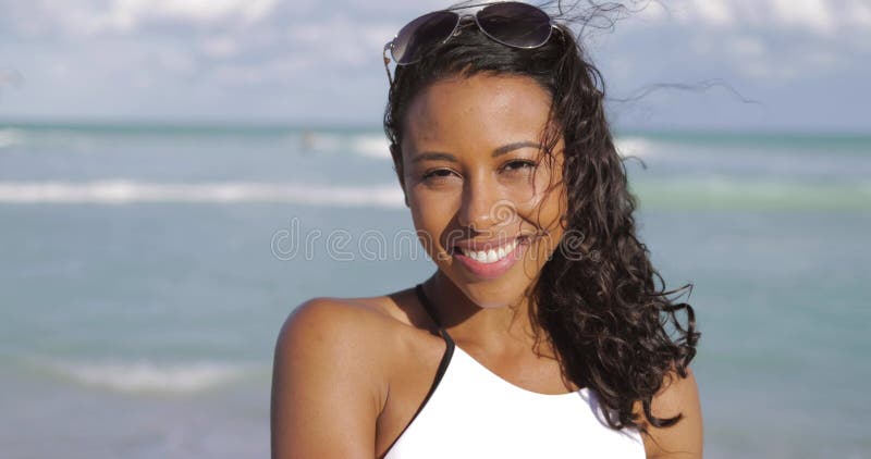 Mujer negra de risa en traje de baño en la playa