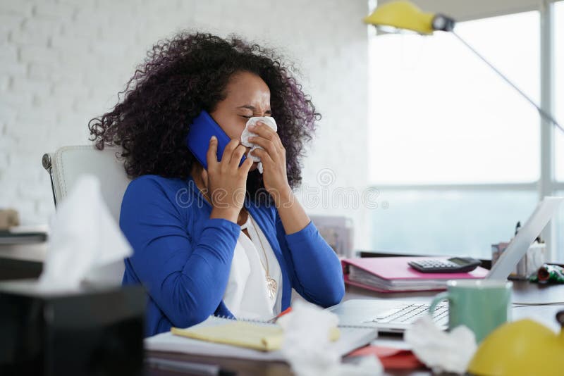 Mujer negra enferma que trabaja del hogar que estornuda para el frío fotos de archivo libres de regalías