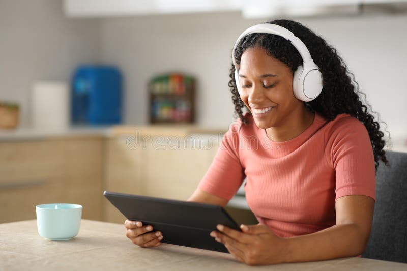 Mujer negra feliz con contenido de tableta para mirar auriculares imágenes de archivo libres de regalías