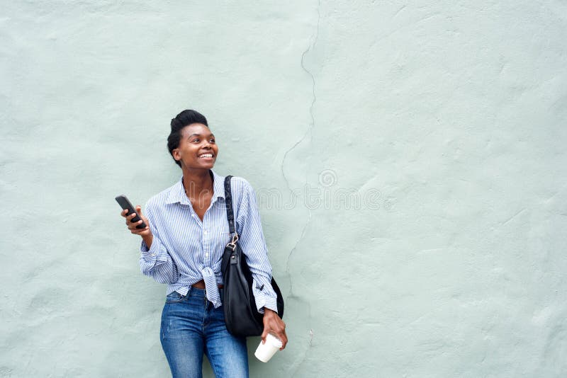 Mujer negra feliz que sostiene el teléfono móvil imagen de archivo