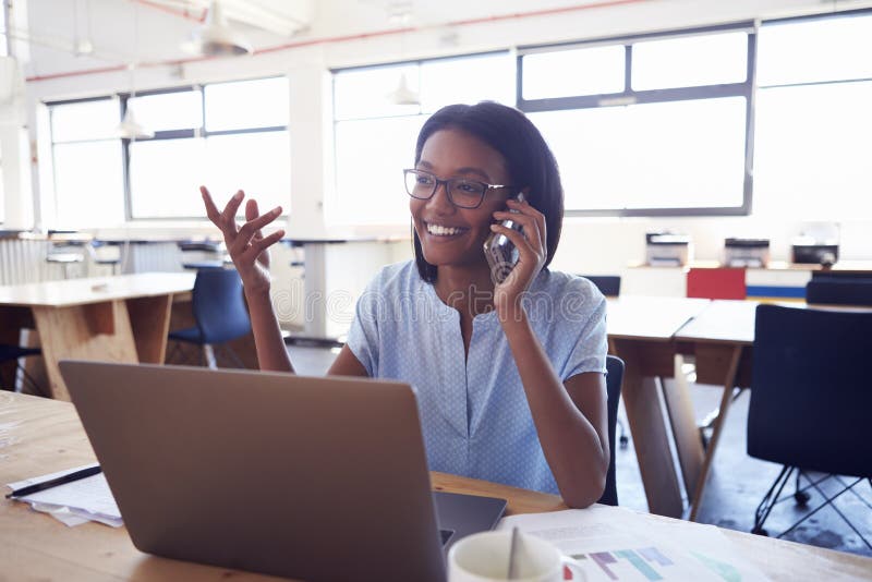 Mujer negra joven en el teléfono en el trabajo en un ½ del ¿del officeï fotos de archivo libres de regalías