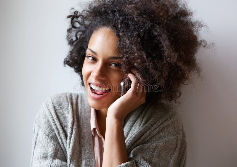Mujer negra joven feliz que habla en el teléfono móvil imagen de archivo libre de regalías Mujer negra joven feliz que habla en el teléfono móvil imagen de archivo libre de regalías