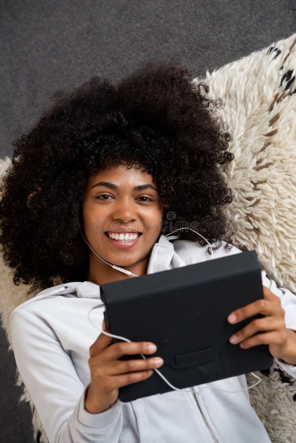 Mujer negra joven hermosa que miente en piso en casa con la tableta digital fotos de archivo libres de regalías Mujer negra joven hermosa que miente en piso en casa con la tableta digital fotos de archivo libres de regalías