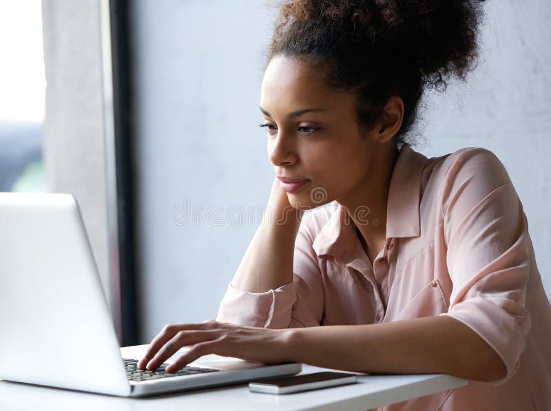 Mujer negra joven que mira el ordenador portátil