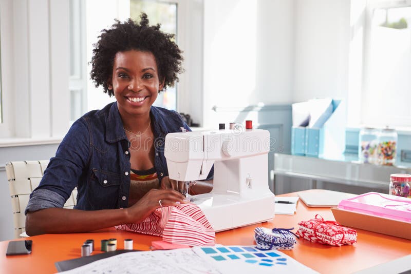 Mujer negra joven que usa una máquina de coser que mira a la cámara imagen de archivo libre de regalías