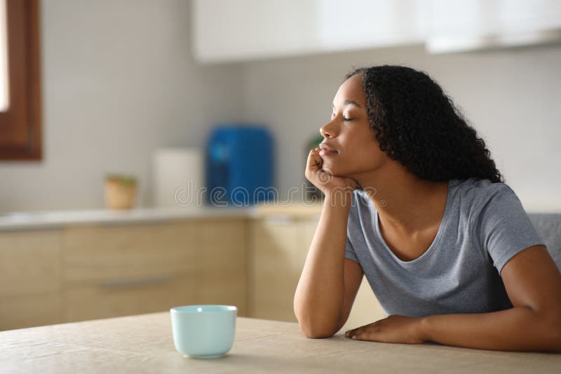 Mujer negra se relaja en la cocina en casa imagen de archivo