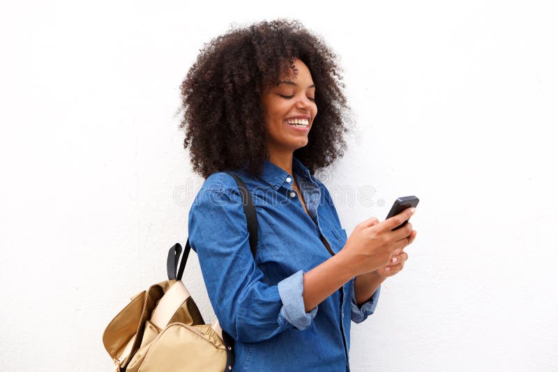 Mujer negra sonriente con el teléfono y la mochila elegantes imagen de archivo libre de regalías