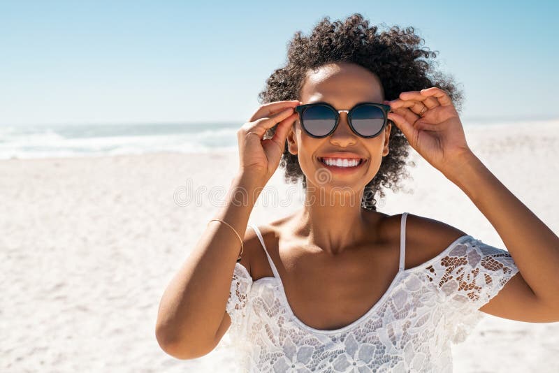 Mujer Negra Sonriente Divirtiéndose En La Playa Mientras Usa Gafas De Sol Imagen de archivo - de sonriente, mirando: 241382285