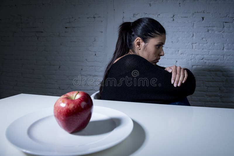 Young woman or teen and apple fruit on dish as symbol of crazy diet in nutrition disorder concept anorexia and bulimia and refusing to eat food in diet calories obsession. Young woman or teen and apple fruit on dish as symbol of crazy diet in nutrition disorder concept anorexia and bulimia and refusing to eat food in diet calories obsession