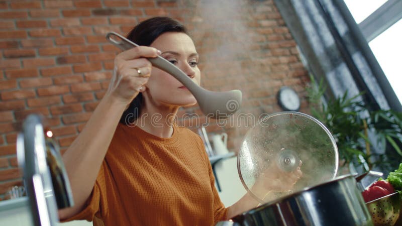 Mujer oliendo sopa caliente en la cocina Comida de caseros en la cocina de la casa