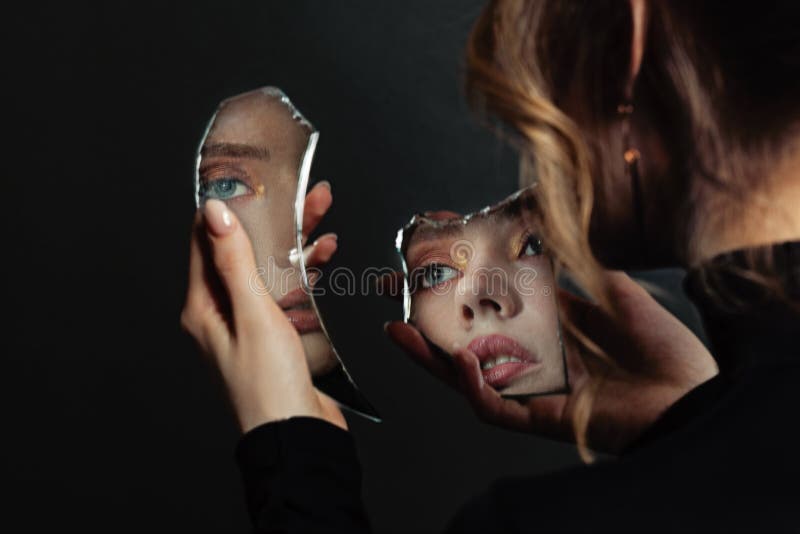 Mujer perfecta mirando el espejo de selfimage roto sobre fondo negro