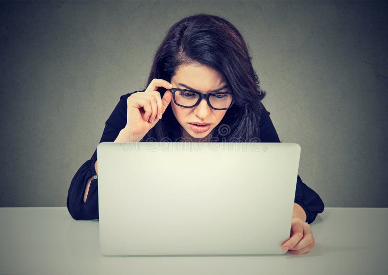 Mujer preocupante que trabaja en el ordenador portátil que mira confundido la pantalla de ordenador