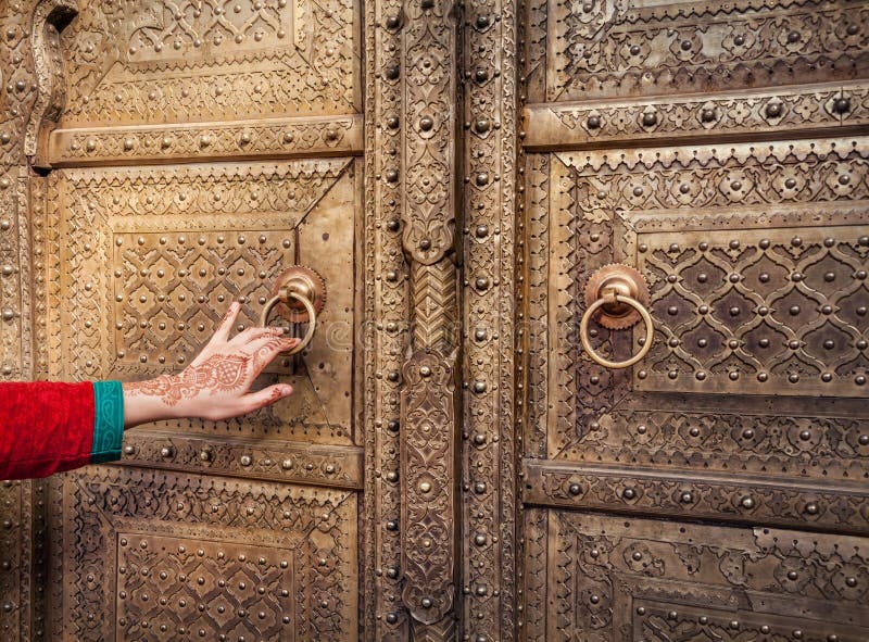 Woman hand with henna painting opening golden door in City Palace of Jaipur, Rajasthan, India. Woman hand with henna painting opening golden door in City Palace of Jaipur, Rajasthan, India