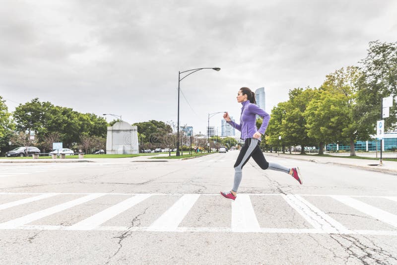 Mujer que activa y que cruza el camino en cebra en Chicago foto de archivo libre de regalías Mujer que activa y que cruza el camino en cebra en Chicago foto de archivo libre de regalías