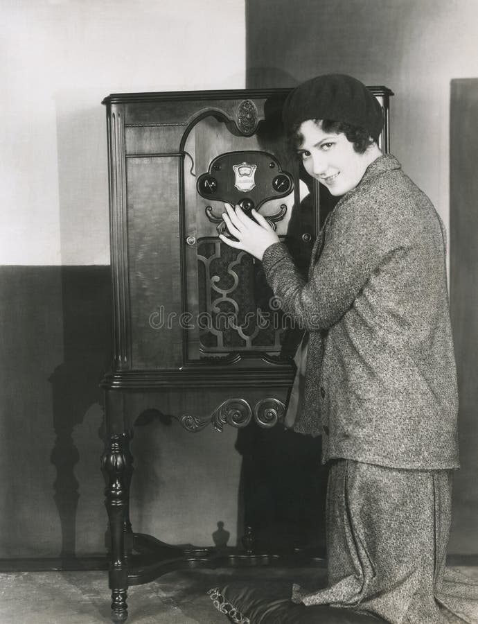 Mujer que ajusta la radio del volumen 1920 s imagen de archivo Mujer que ajusta la radio del volumen 1920 s imagen de archivo