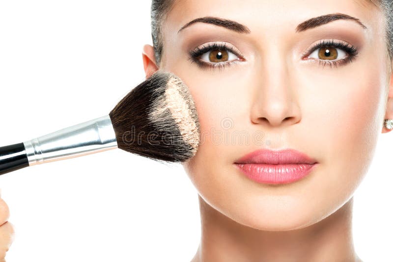 Closeup portrait of a woman applying dry cosmetic tonal foundation on the face using makeup brush. Closeup portrait of a woman applying dry cosmetic tonal foundation on the face using makeup brush.