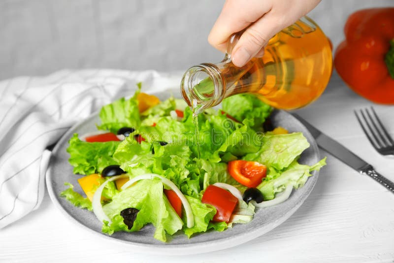 Mujer que añade el vinagre sabroso de la manzana en la ensalada fotos de archivo Mujer que añade el vinagre sabroso de la manzana en la ensalada fotos de archivo