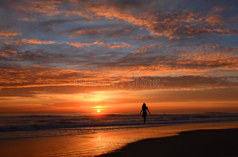 Mujer que camina en la playa en la salida del sol fotos de archivo libres de regalías Mujer que camina en la playa en la salida del sol fotos de archivo libres de regalías