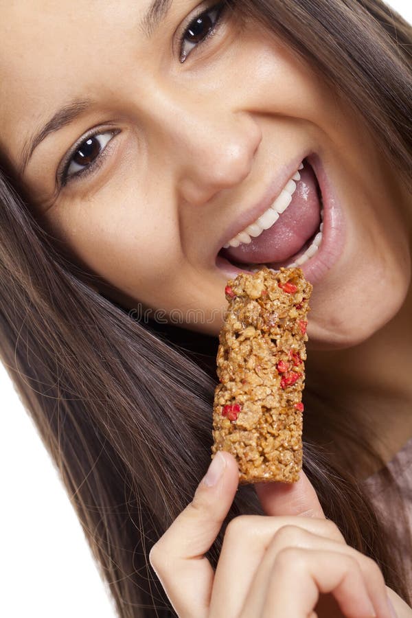 Mujer que come la barra de caramelo del cereal fotografía de archivo libre de regalías Mujer que come la barra de caramelo del cereal fotografía de archivo libre de regalías