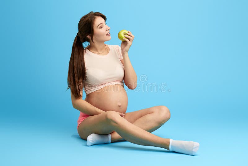 Mujer que come manzana verde con el estómago grande, vitamina para el bebé imagenes de archivo Mujer que come manzana verde con el estómago grande, vitamina para el bebé imagenes de archivo