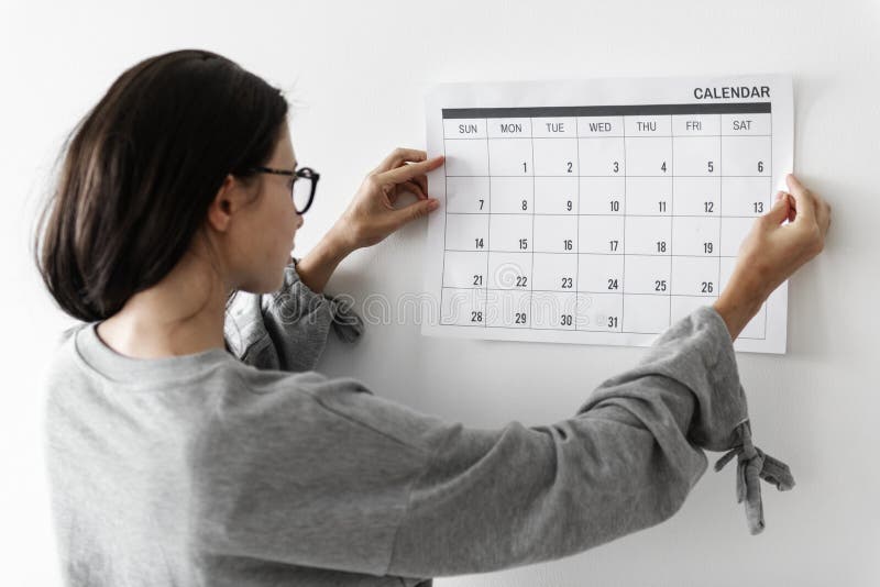 Mujer que comprueba el calendario en la pared