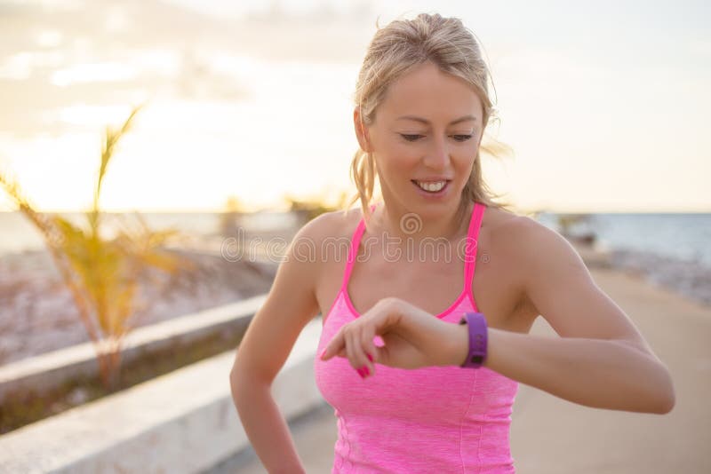 Mujer que comprueba su dispositivo elegante del reloj de la aptitud fotografía de archivo Mujer que comprueba su dispositivo elegante del reloj de la aptitud fotografía de archivo