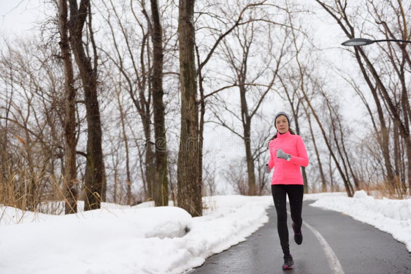 Mujer que corre en el parque nevoso de la ciudad - aptitud del invierno imagen de archivo libre de regalías Mujer que corre en el parque nevoso de la ciudad - aptitud del invierno imagen de archivo libre de regalías