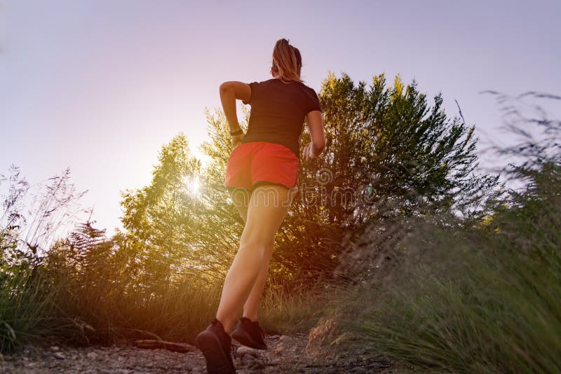 Mujer que corre en las monta?as en la puesta del sol foto de archivo libre de regalías Mujer que corre en las monta?as en la puesta del sol foto de archivo libre de regalías