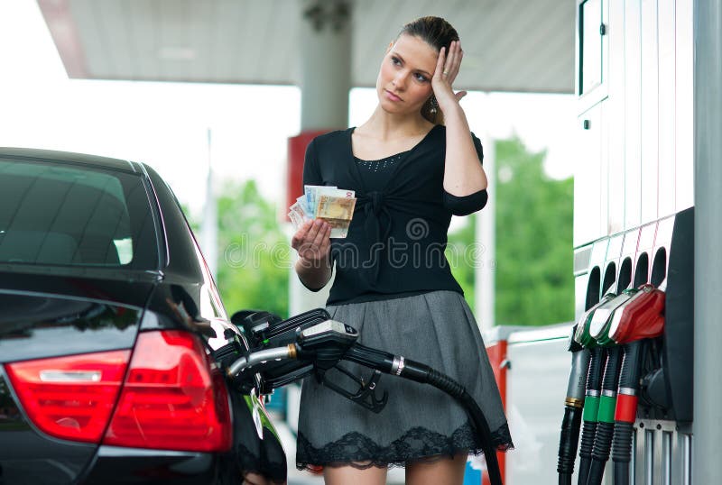 Mujer que cuenta el dinero en la gasolinera