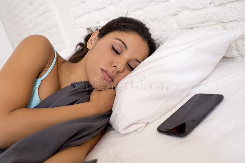 Mujer que duerme en cama en casa así como el teléfono móvil en el apego del Internet fotos de archivo libres de regalías Mujer que duerme en cama en casa así como el teléfono móvil en el apego del Internet fotos de archivo libres de regalías