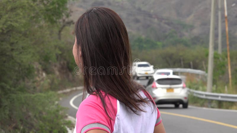 Mujer que espera por el tráfico por carretera