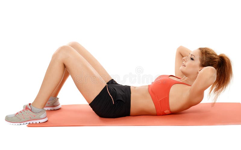 Mujer que hace crujidos del ABS en una estera fotografía de archivo Mujer que hace crujidos del ABS en una estera fotografía de archivo