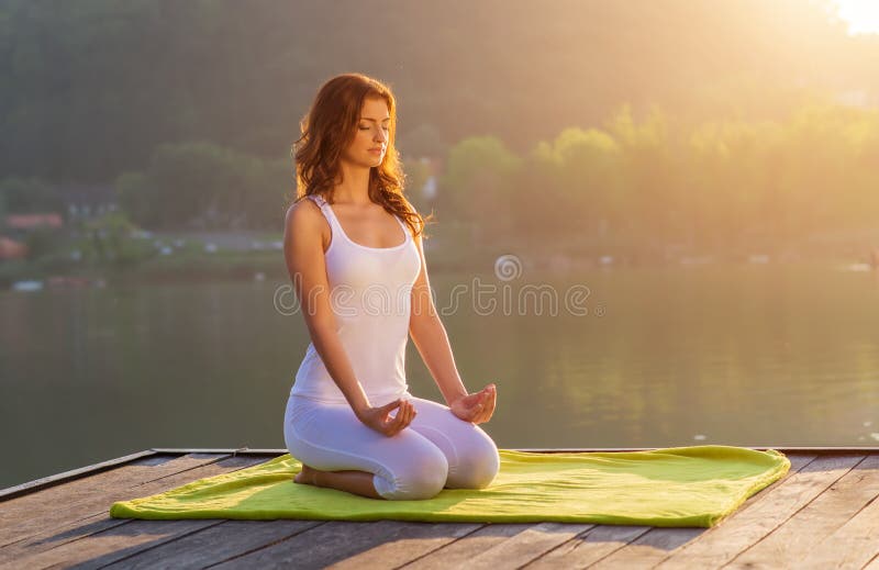 Mujer que hace la yoga en la orilla - media figura sentada imágenes de archivo libres de regalías