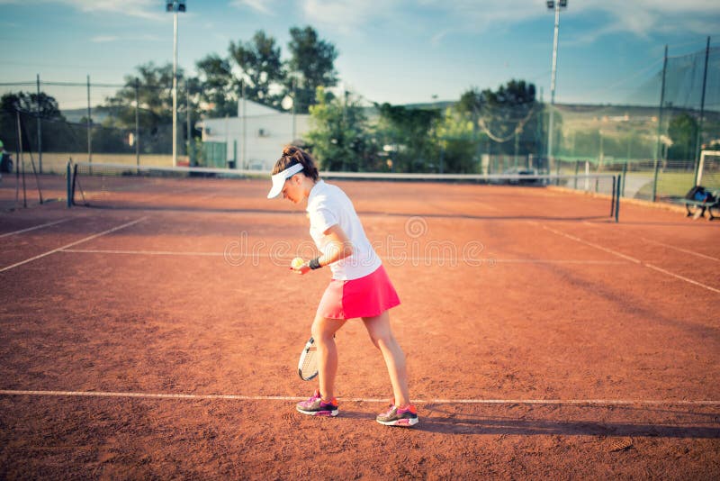 Mujer que juega a tenis en corte de arcilla, con el equipo deportivo y la forma de vida sana fotografía de archivo Mujer que juega a tenis en corte de arcilla, con el equipo deportivo y la forma de vida sana fotografía de archivo