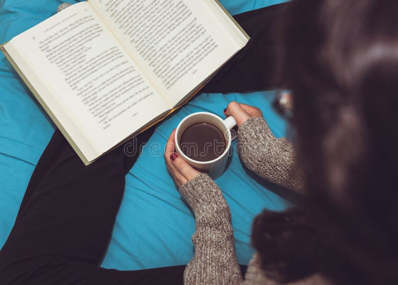 Mujer que lee un libro y que bebe el café en cama imágenes de archivo libres de regalías Mujer que lee un libro y que bebe el café en cama imágenes de archivo libres de regalías