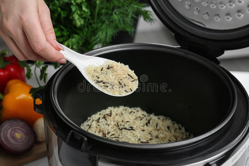 Mujer que llena la cocina multi de arroz imagenes de archivo Mujer que llena la cocina multi de arroz imagenes de archivo