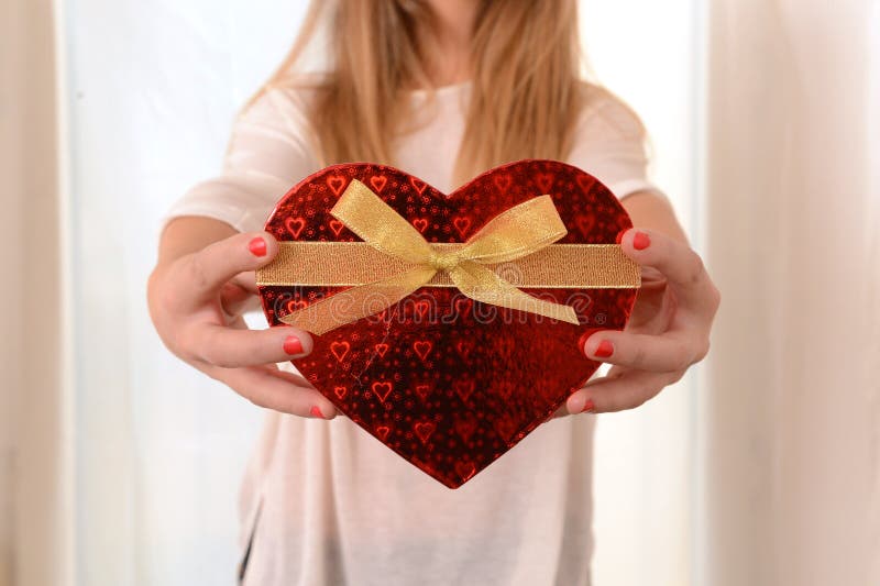 Mujer que lleva a cabo el presente en forma de corazón de la caja imagen de archivo Mujer que lleva a cabo el presente en forma de corazón de la caja imagen de archivo