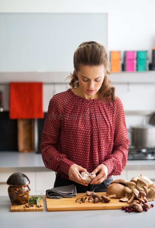 Mujer que mira abajo en la cocina que prepara el ajo y setas fotos de archivo Mujer que mira abajo en la cocina que prepara el ajo y setas fotos de archivo
