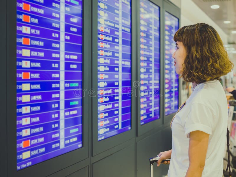 Mujer que mira al tablero de la información en término del aeropuerto internacional fotos de archivo Mujer que mira al tablero de la información en término del aeropuerto internacional fotos de archivo
